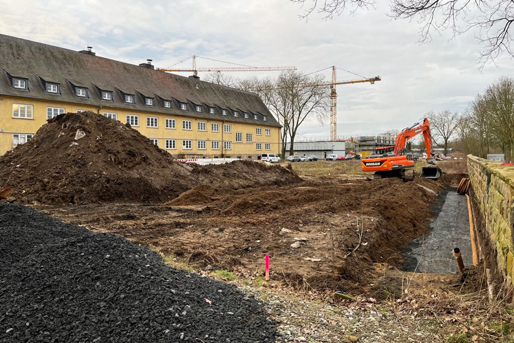 Aushub auf dem Baufeld entlang der historischen Sandsteinmauer